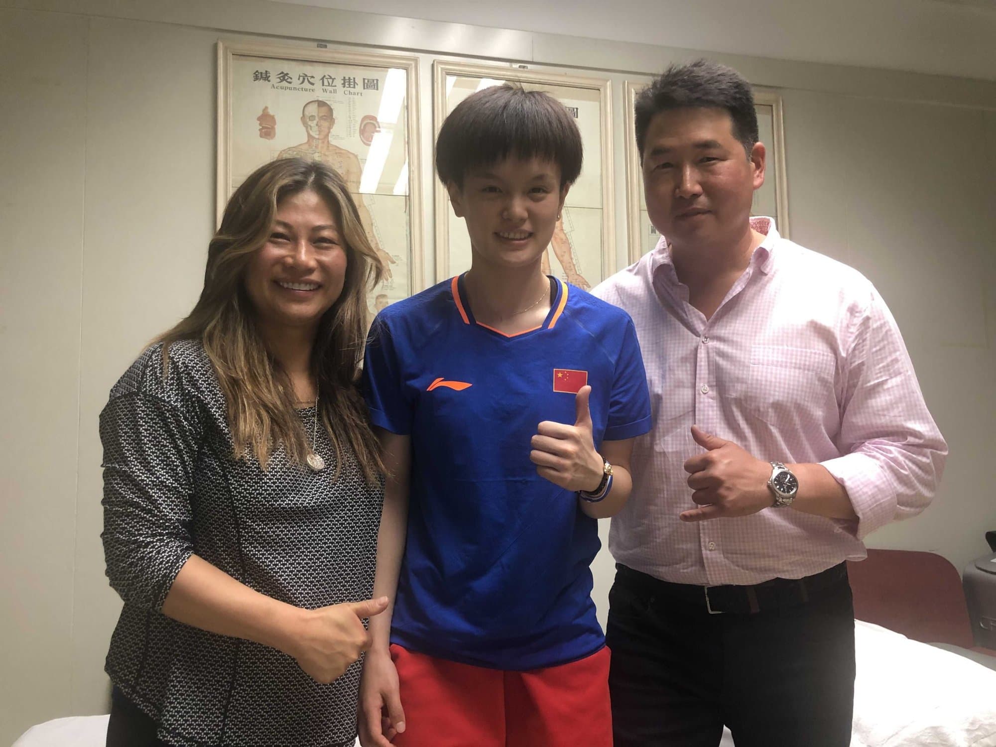 Dr. Koh and a colleague standing with an athlete in a red and blue China team shirt