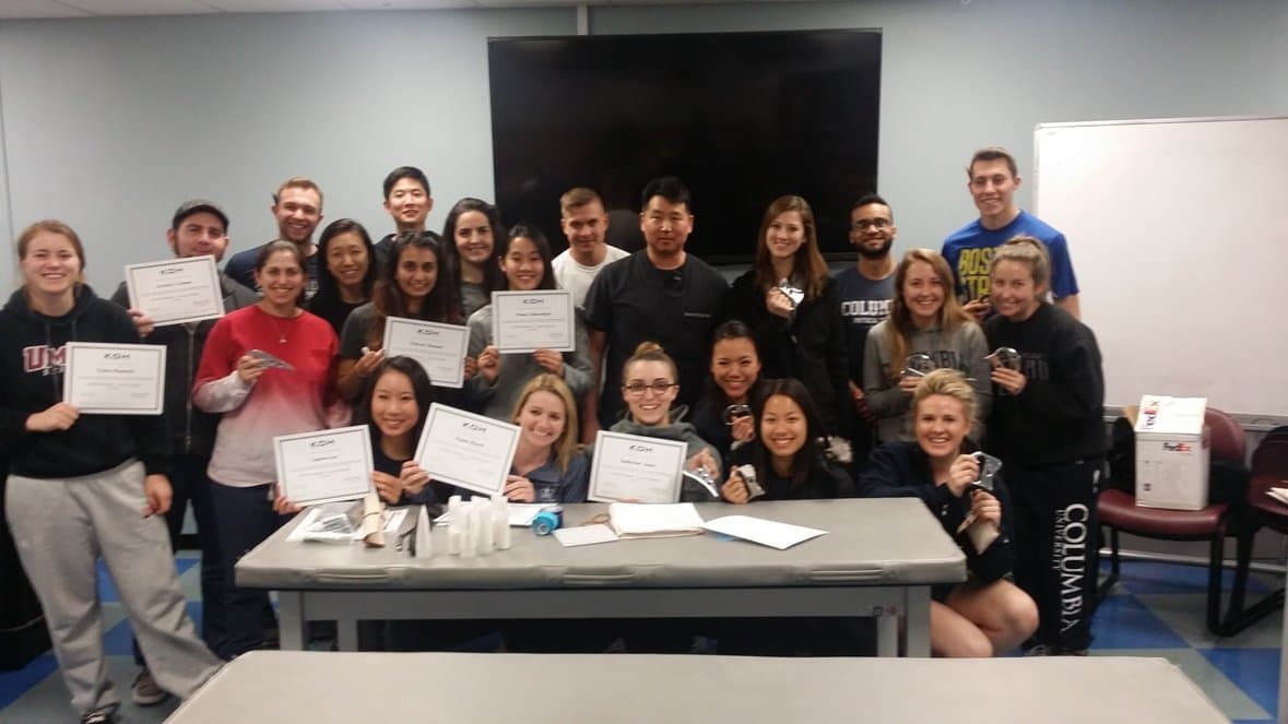 A group of course attendees holding certificates in a classroom