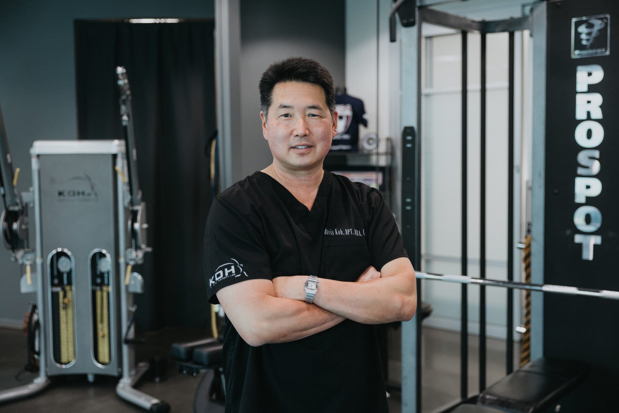 Davis Koh, PT, DPT, GCS, CSCS, standing with arms crossed in the KOH Physical Therapy Lab clinic