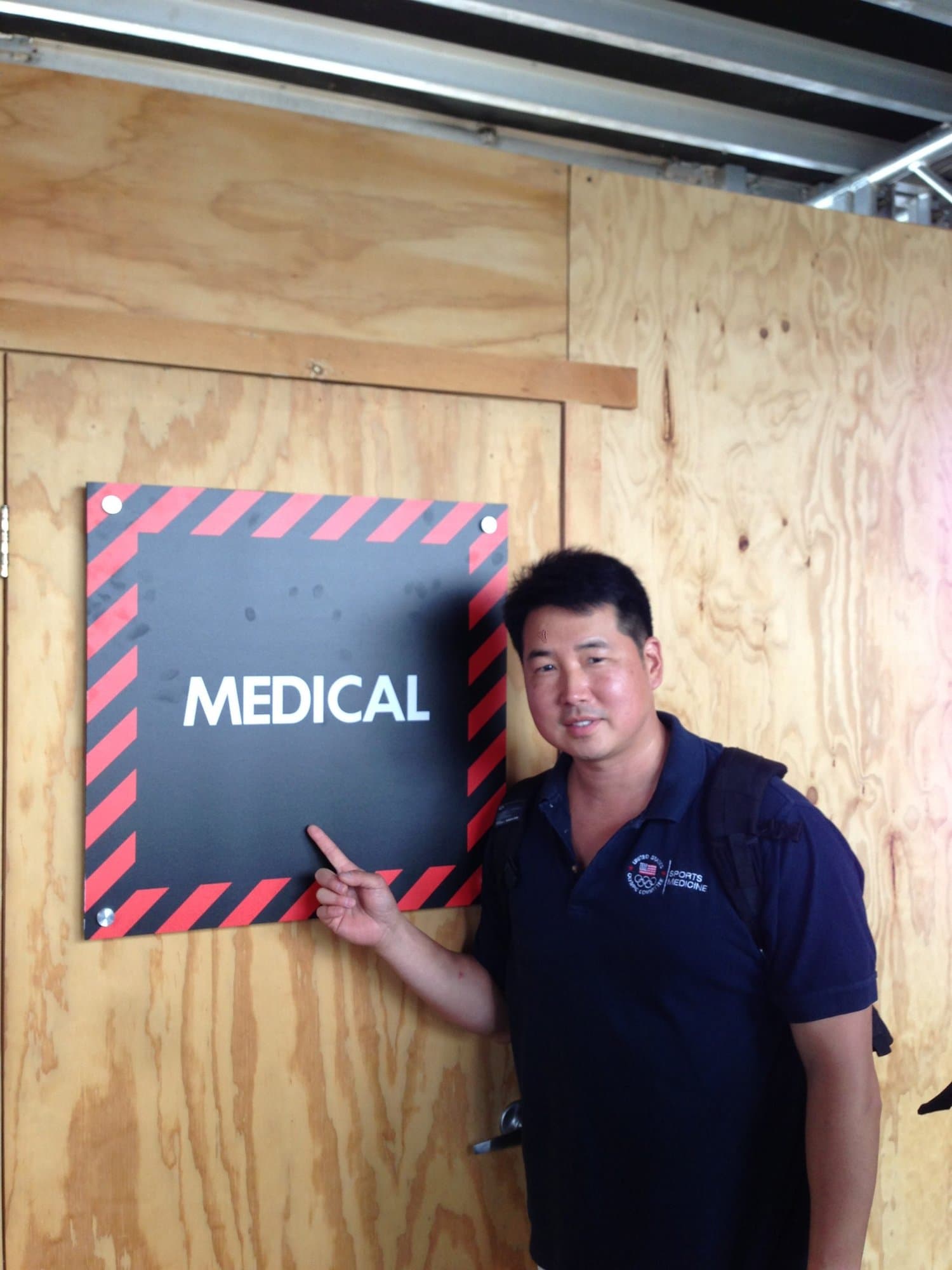 Dr. Koh pointing at a Medical sign on a plywood wall at an event