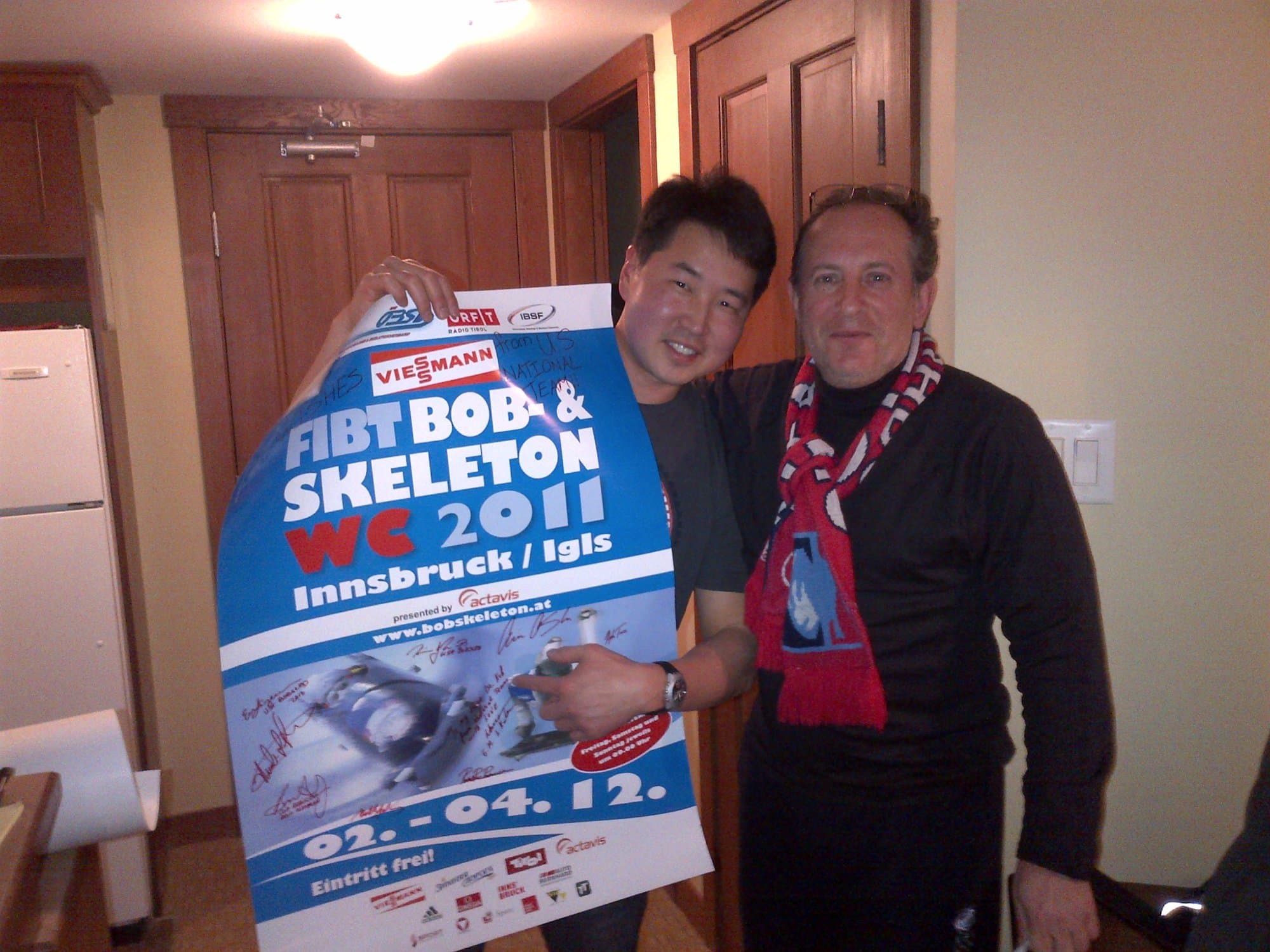 Dr. Koh and a colleague holding a FIBT Bob and Skeleton World Cup 2012 poster