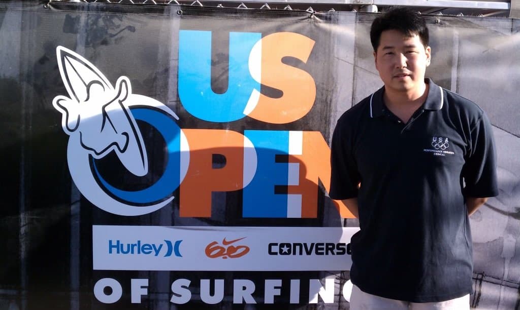 Dr. Koh standing beside a US Open of Surfing banner
