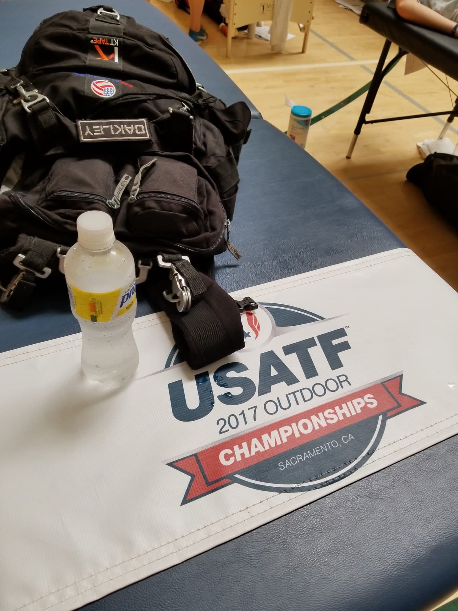 A medical kit bag and water bottle on a treatment table covered with a USATF 2017 Outdoor Championships banner