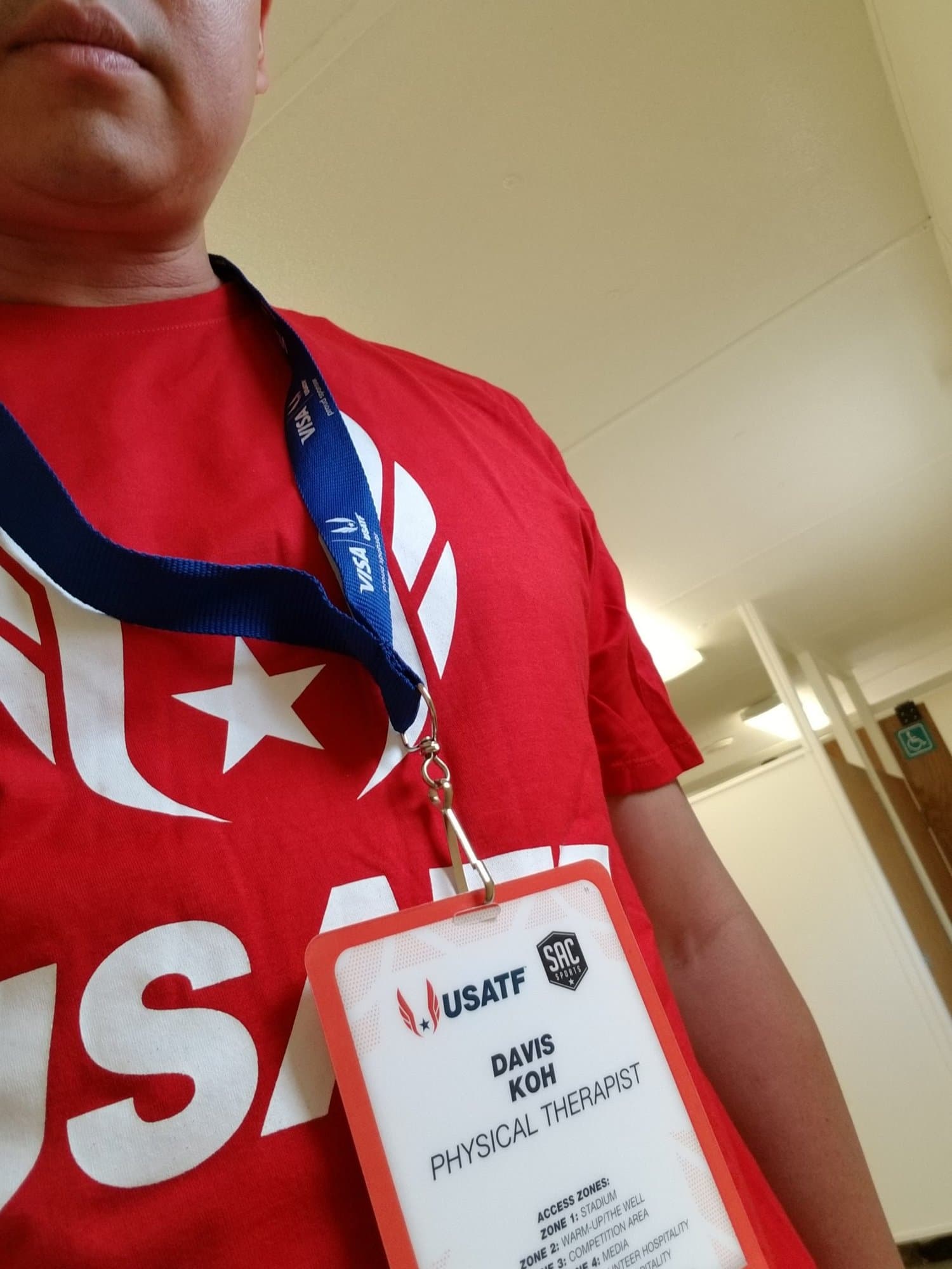 A USATF credential reading Davis Koh, Physical Therapist, worn over a red USA shirt